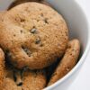 A close-up of freshly baked chocolate chip cookies in a white bowl, perfect for food blogs.